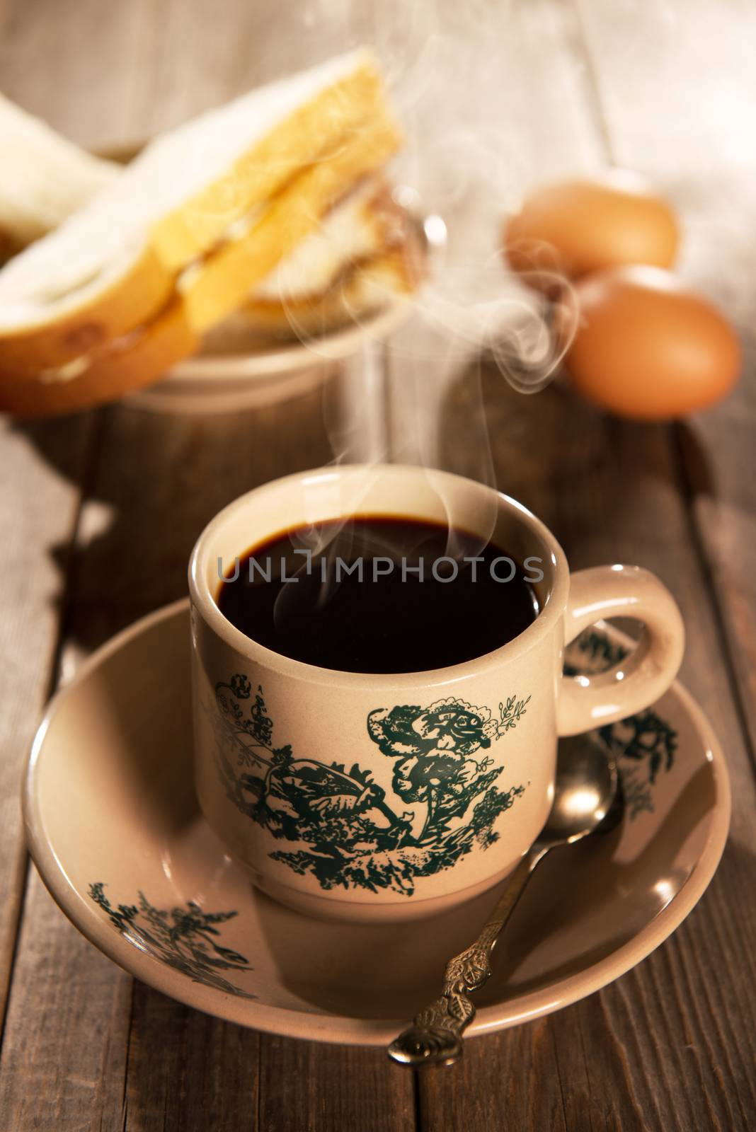 Traditional Singapore Chinese style coffee in vintage mug and saucer with breakfast. Fractal on the cup is generic print. Soft focus dramatic ambient light over wood table.