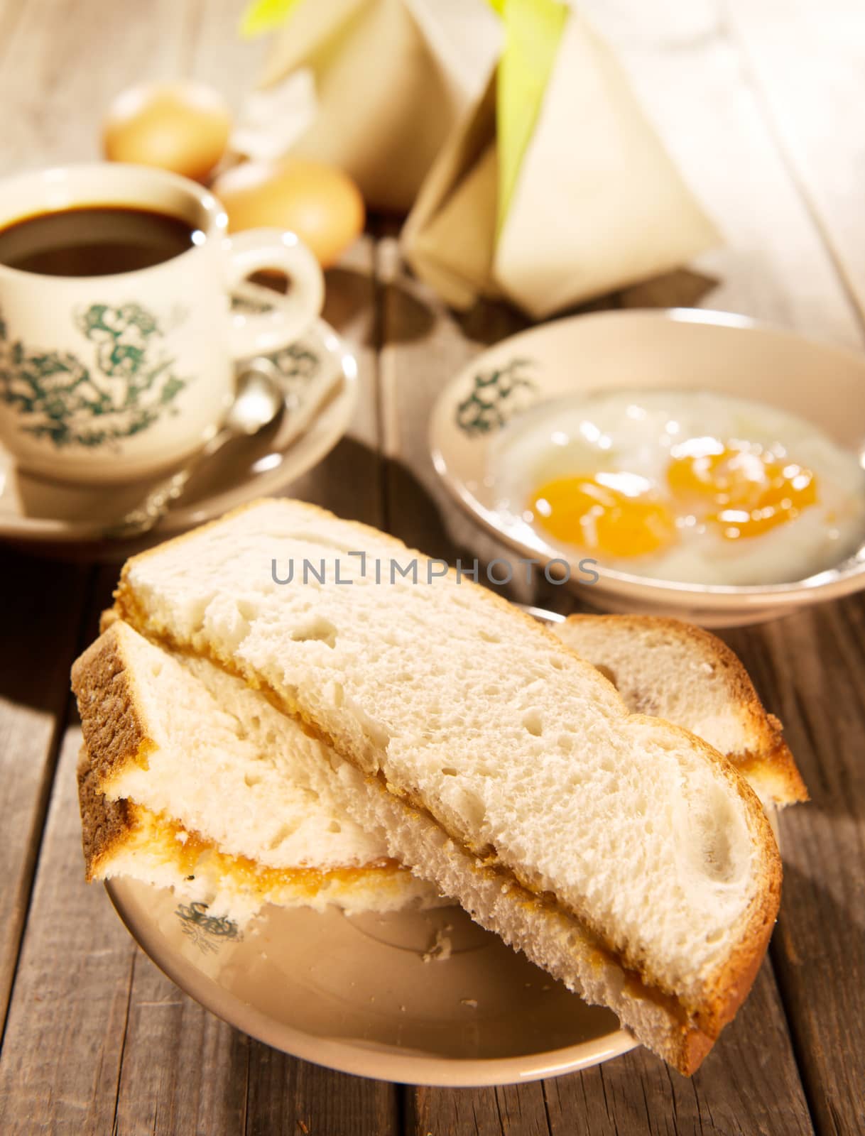 Traditional Chinese Malaysian style breakfast, kaya butter toast, nasi lemak and boiled eggs with coffee. Fractal on the cup is generic print. Soft focus setting with dramatic ambient light on dark wooden background.