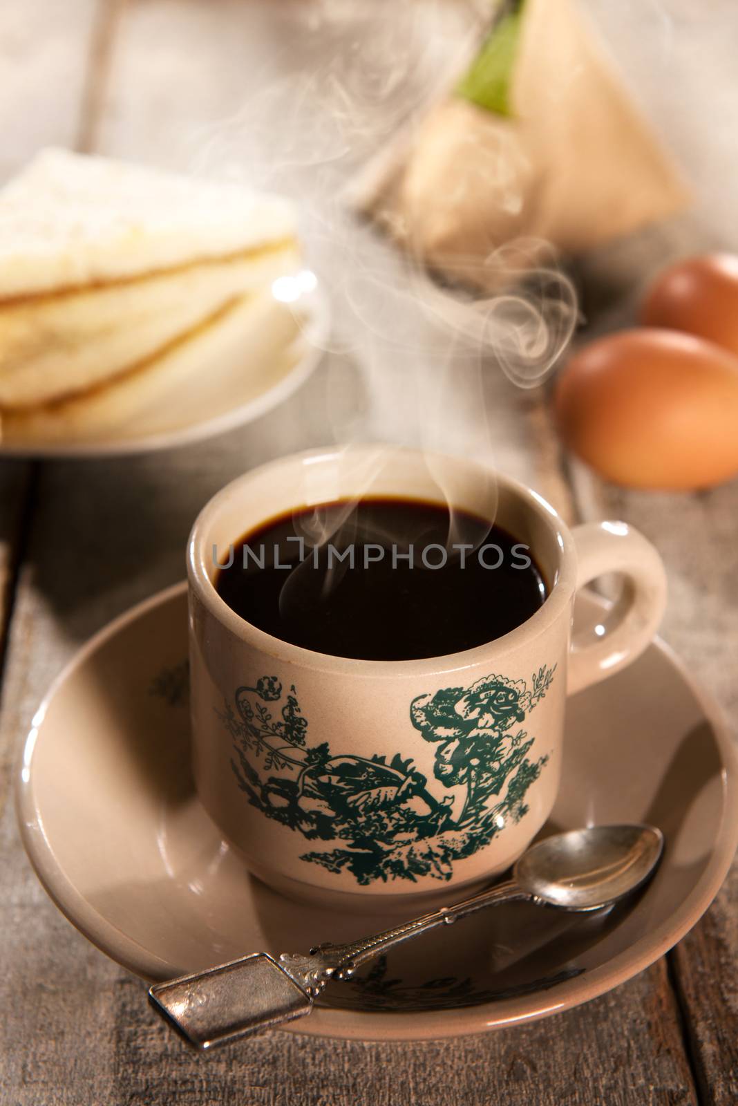 Traditional kopitiam style Malaysian coffee and breakfast with morning sunlight. Fractal on the cup is generic print. Soft focus setting with dramatic ambient light on dark wooden background.