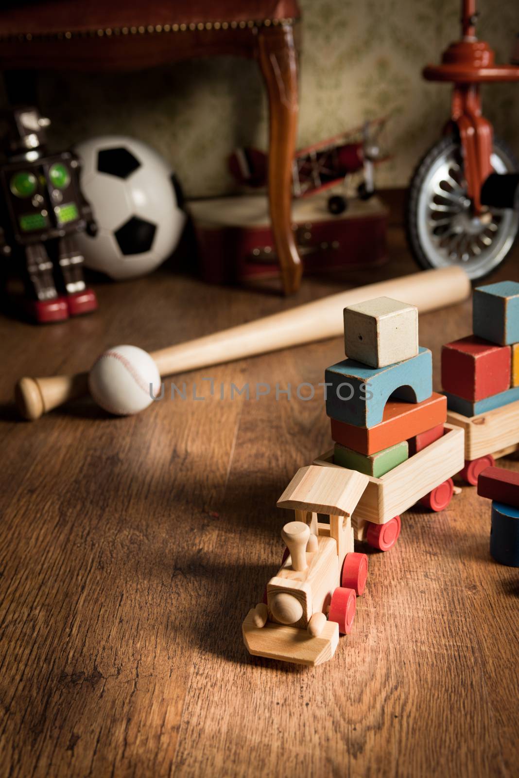 Wooden train and vintage colorful toys on hardwood floor and retro wallpaper on background.
