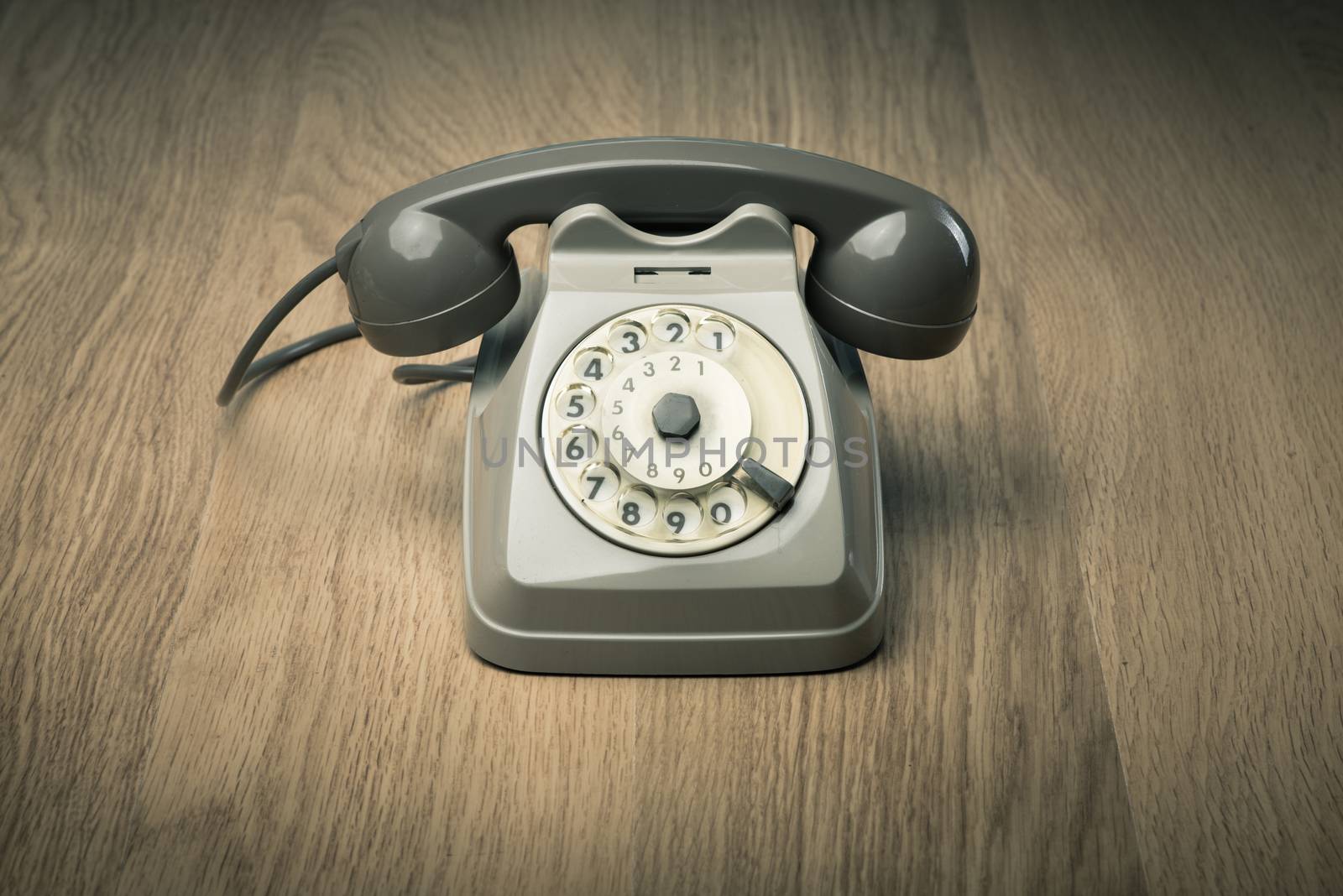 Vintage gray telephone on hardwood surface desk or floor.