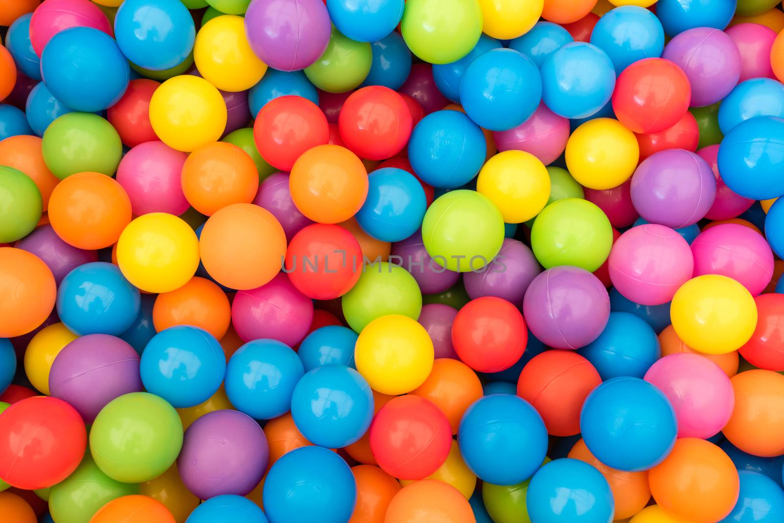 Many colorful plastic balls in a kids' ballpit at a playground.