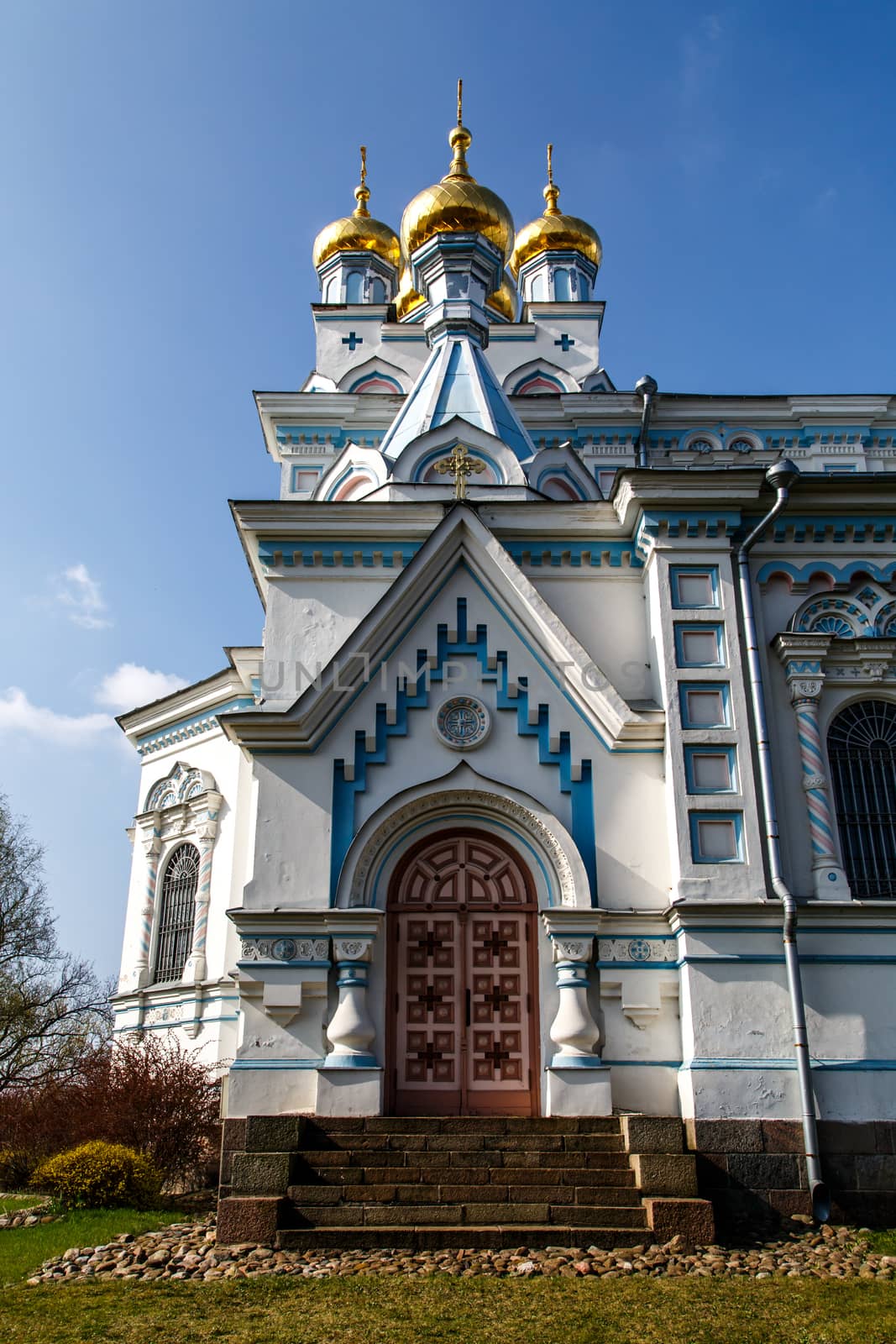 Front view of Orthodox Ss Boris and Gleb Cathedral in Dougavpils, Latvia, on blue cloudy sky background.
