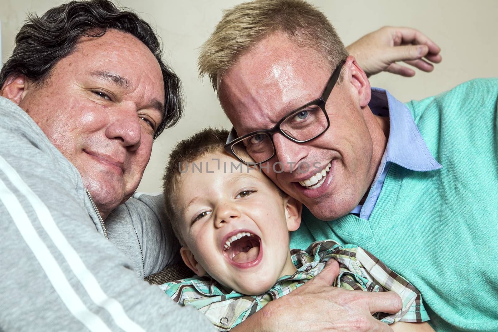 Two gay men hug their happy young son