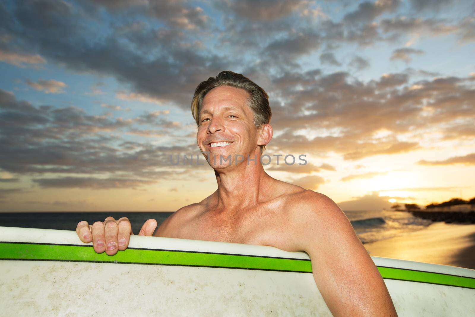 One adult Caucasian surfer with surfboard at sunset