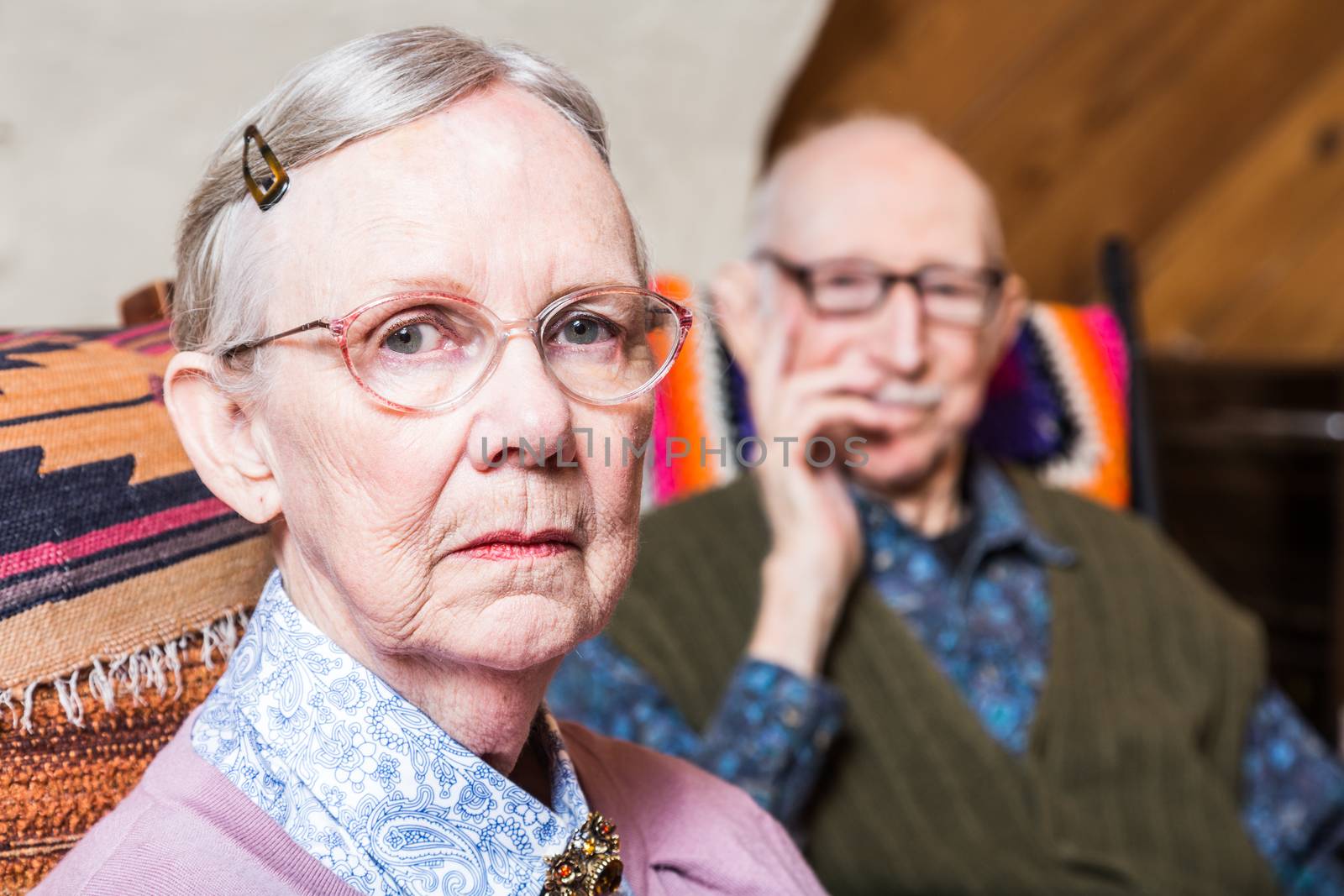 Elderly couple looking seriouds seated in livingroom