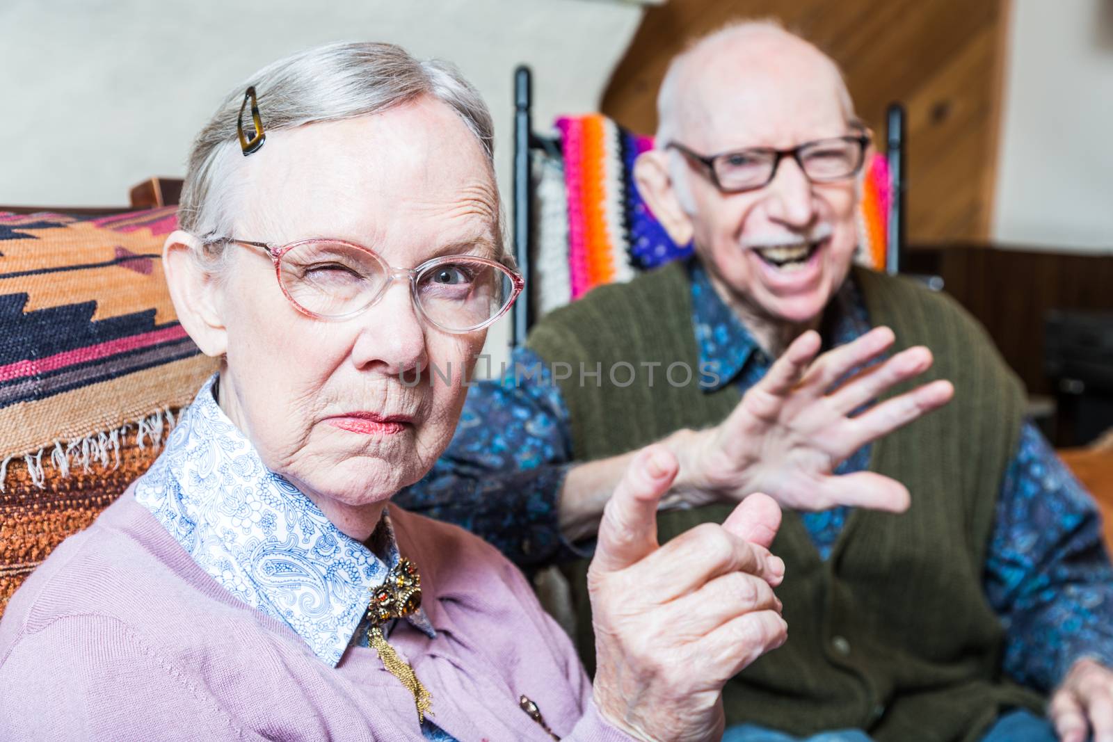 Angry old couple sitting in living room woman pointing