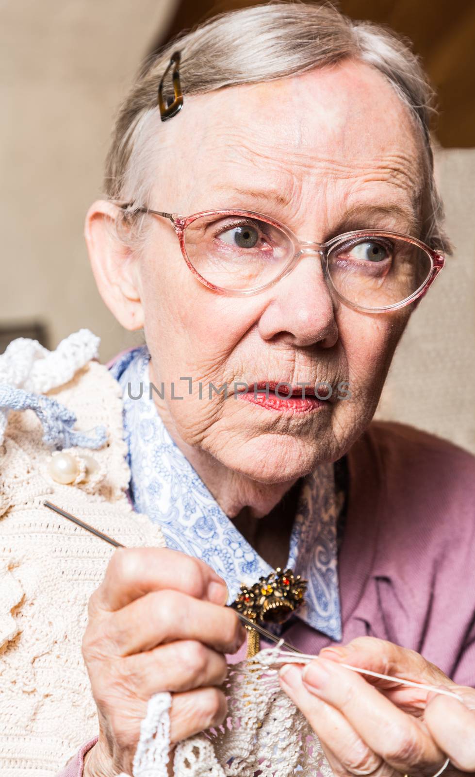 Old woman crocheting with worried expression