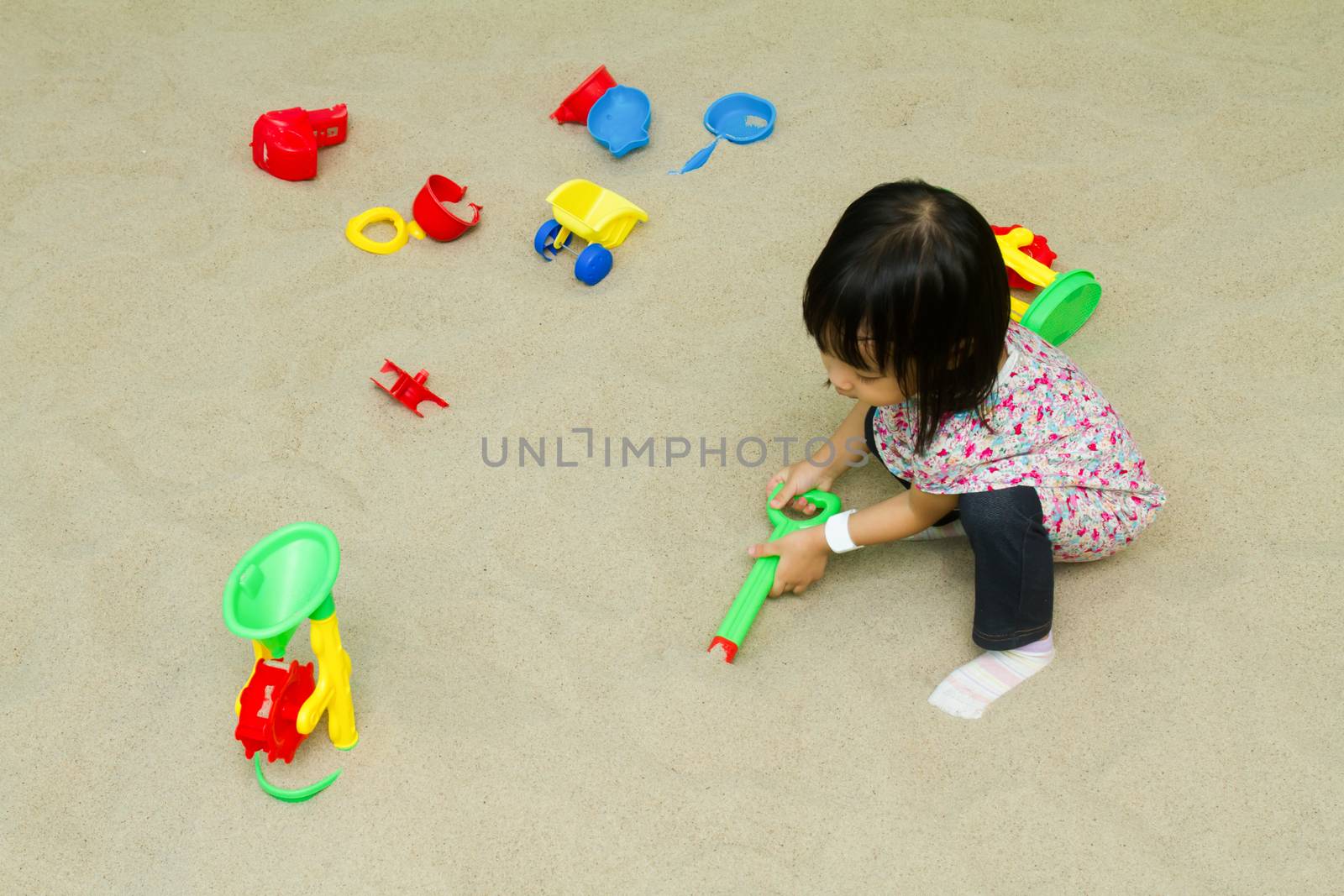 Asian Chinese little girl playing sand at indoor playground.