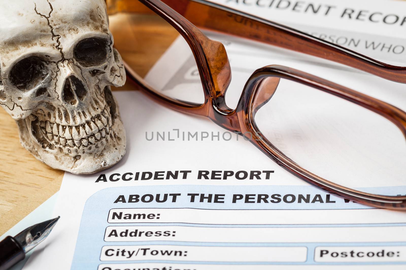 Accident report application form and human skull on brown envelo by FrameAngel