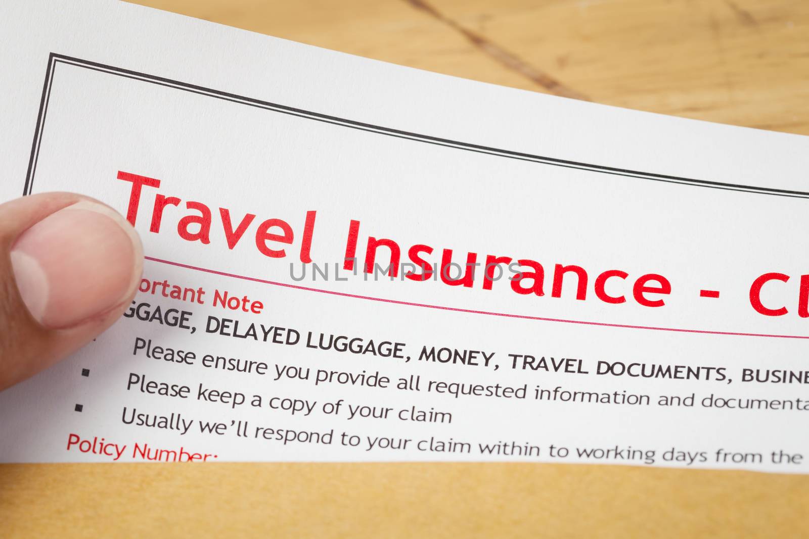 Travel Insurance Claim application form and human hand on brown  by FrameAngel