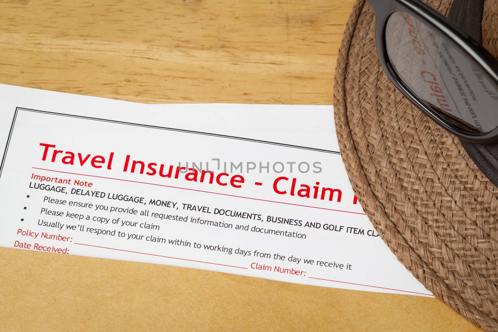 Travel Insurance Claim application form and hat with eyeglass on brown envelope, business insurance and risk concept; document is mock-up