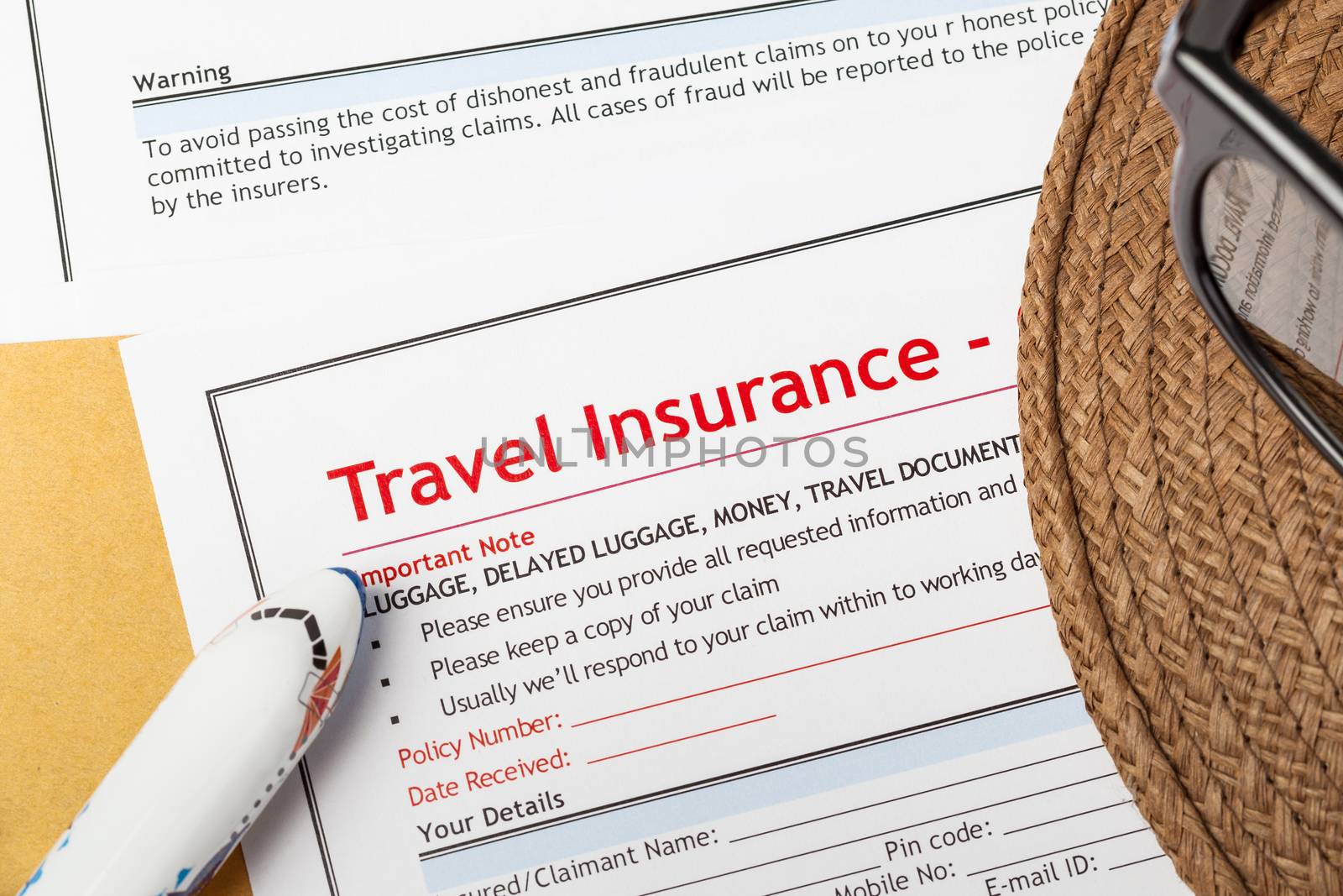 Travel Insurance Claim application form and hat with eyeglass on brown envelope, business insurance and risk concept; document and plane is mock-up