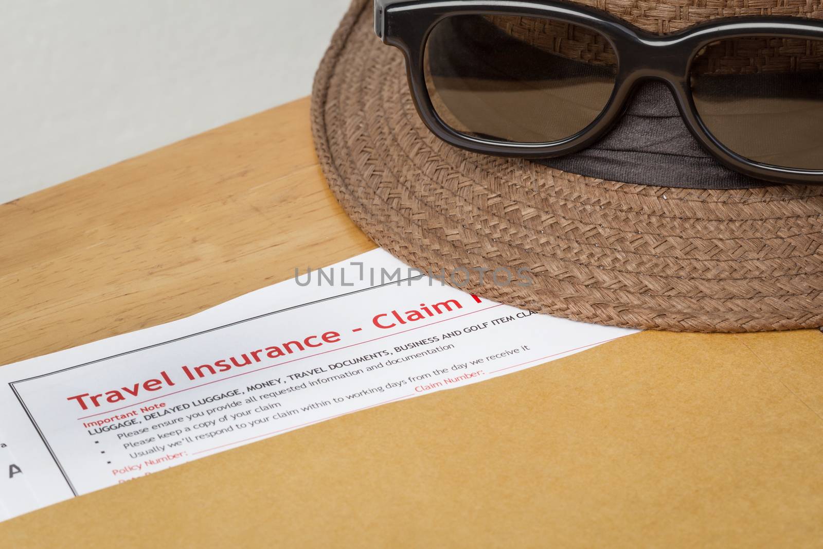 Travel Insurance Claim application form and hat with eyeglass on brown envelope, business insurance and risk concept; document is mock-up