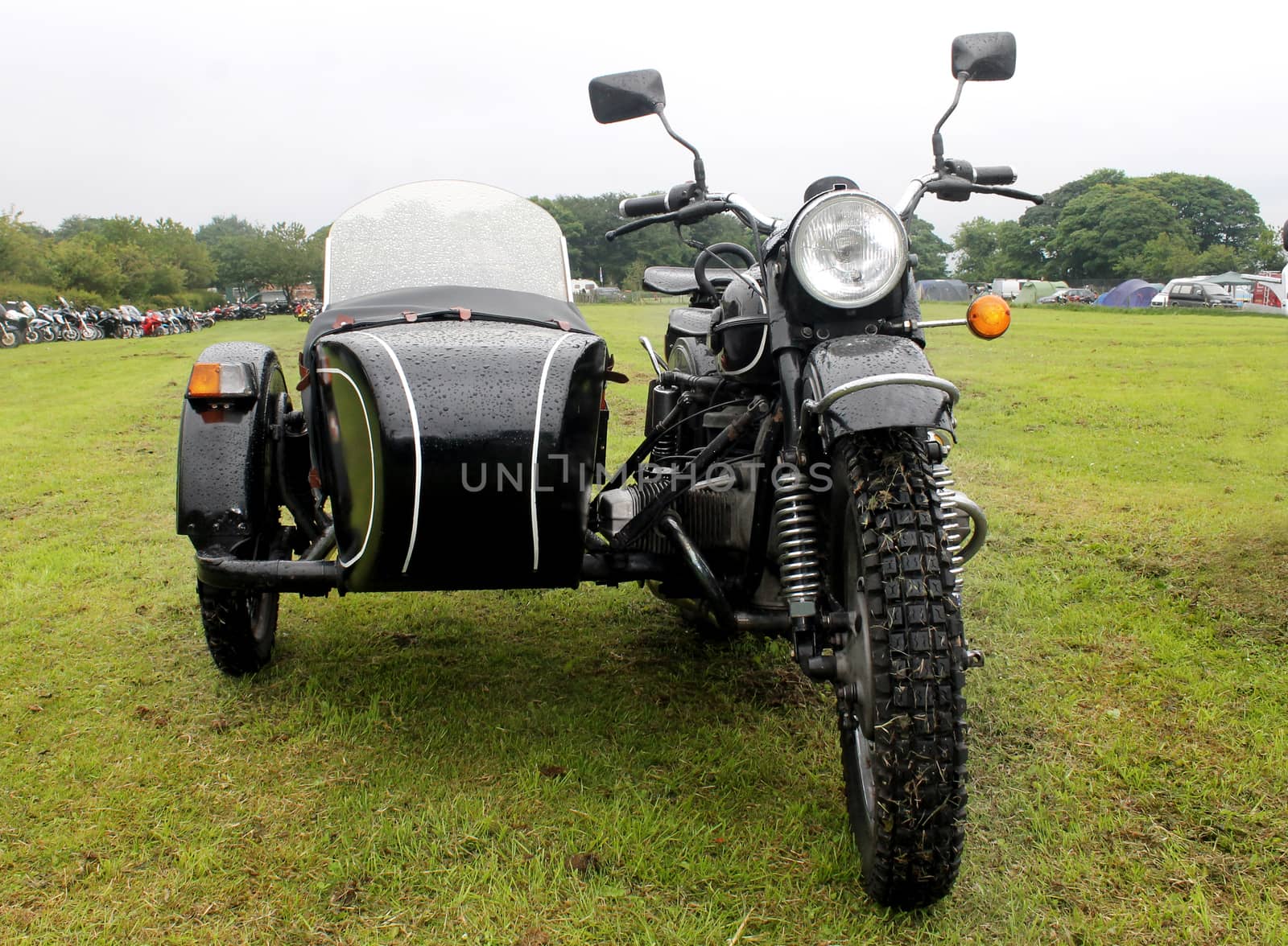 Motorbike and sidecar in a countryside field.
