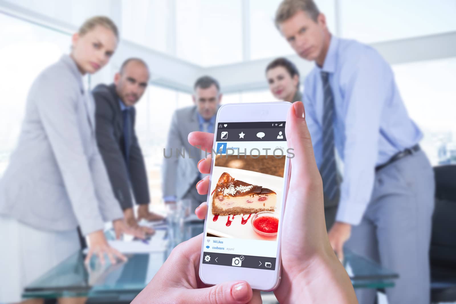 Hand holding smartphone against cheesecake with chantilly cream and coulis