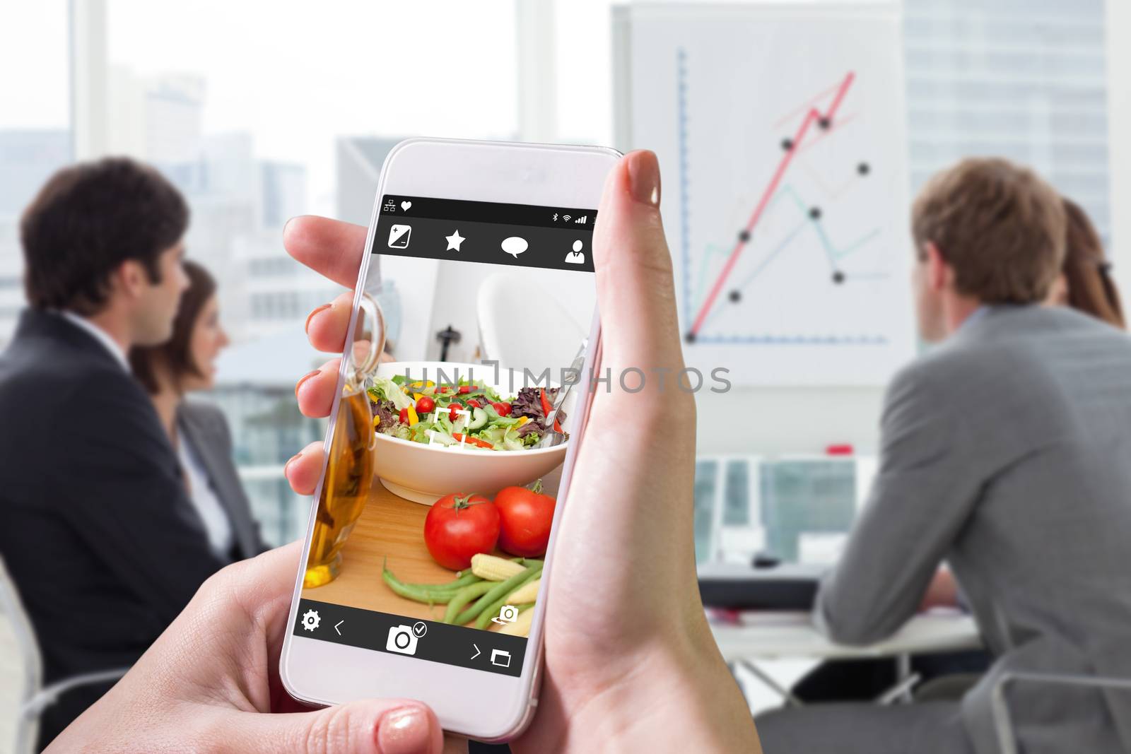Hand holding smartphone against close up of salad