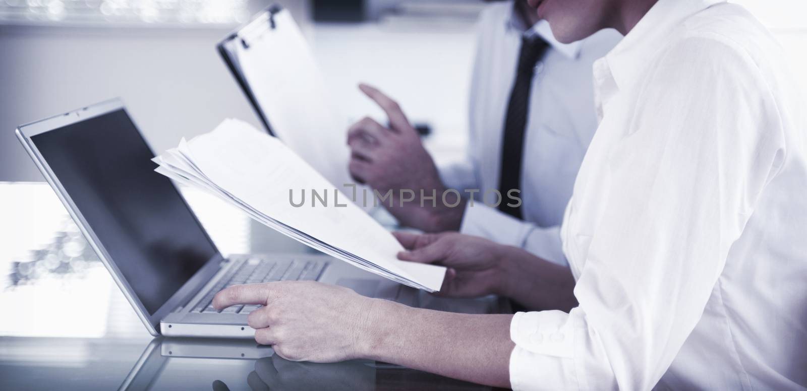 Office workers typing a report from blueprint documents in an office