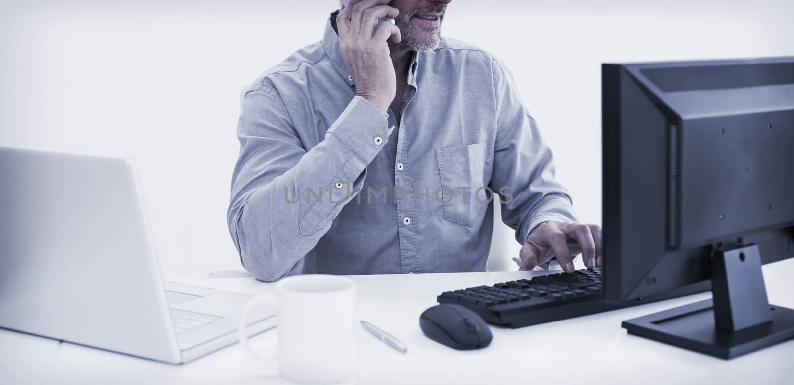 Businessman with cellphone, laptop and computer at desk by Wavebreakmedia