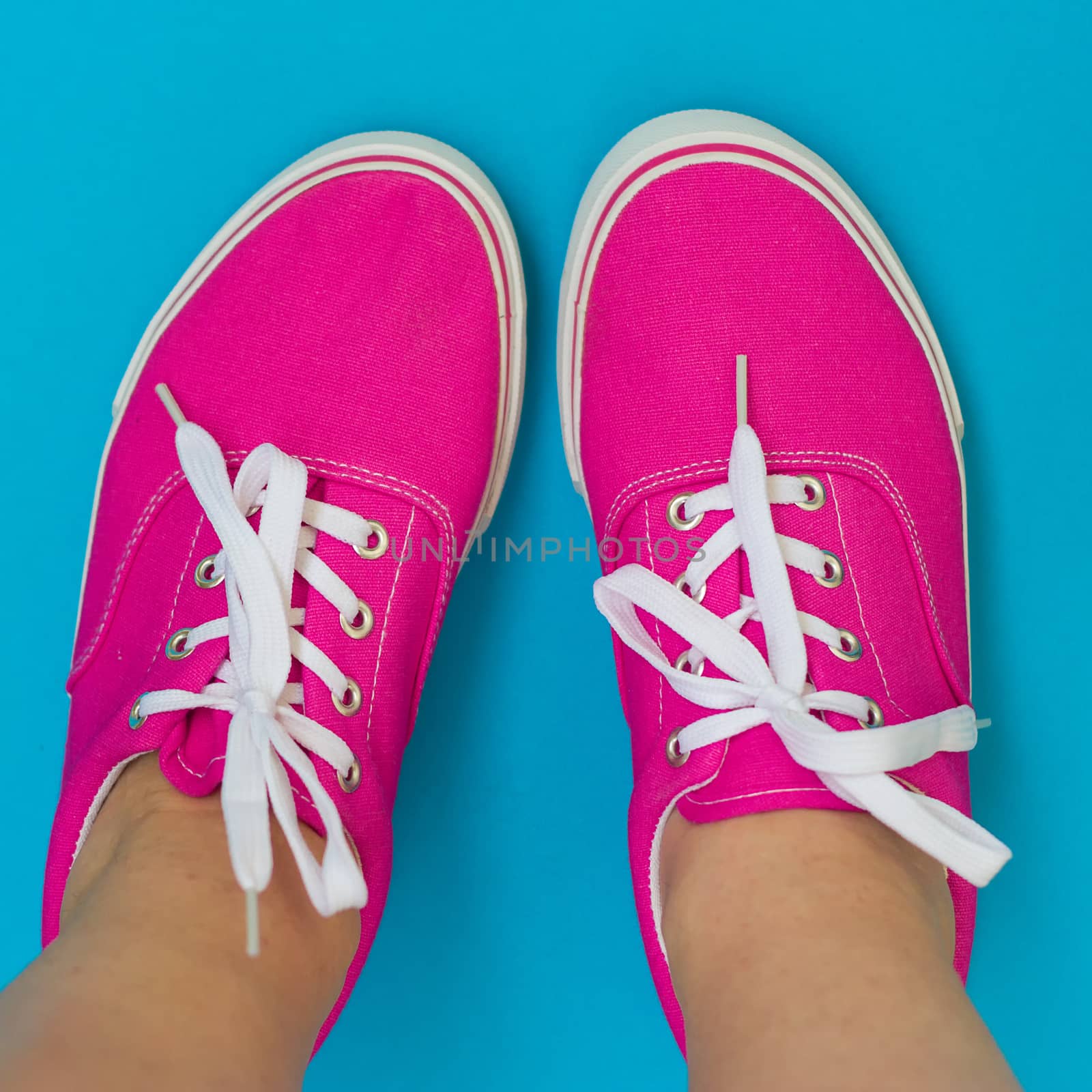 Legs in pink sneakers on blue background by victosha