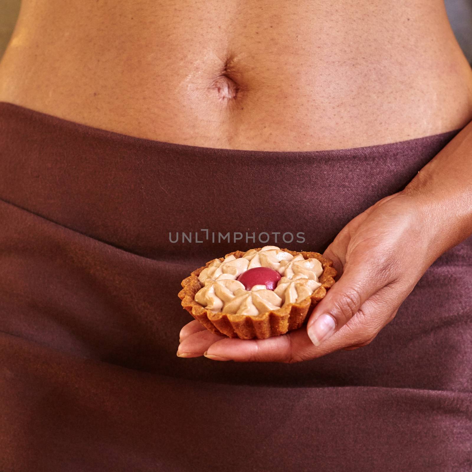 Dessert in the hand at the level of the abdomen. Temptation concept