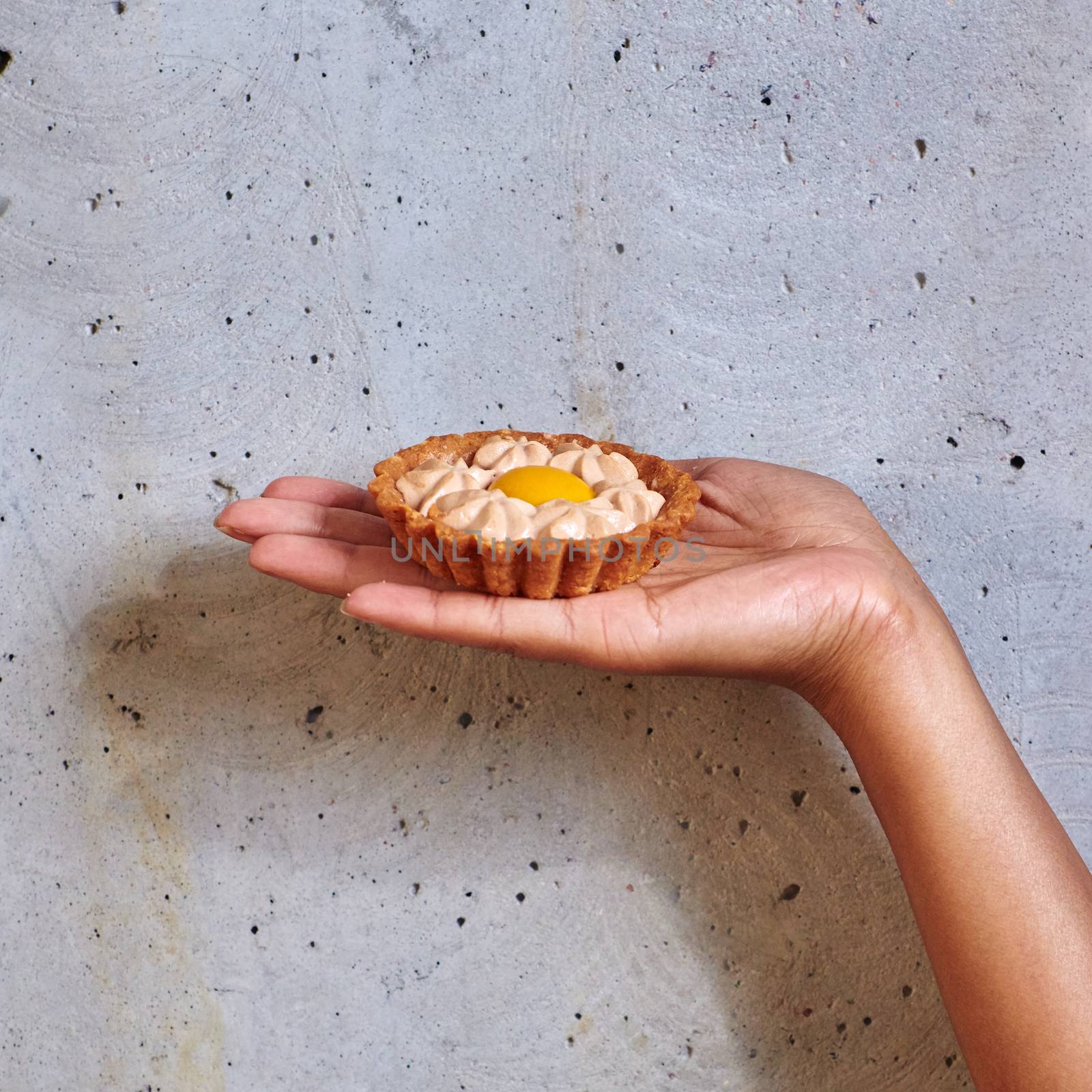 Dessert in a hand on a concrete background with copy space