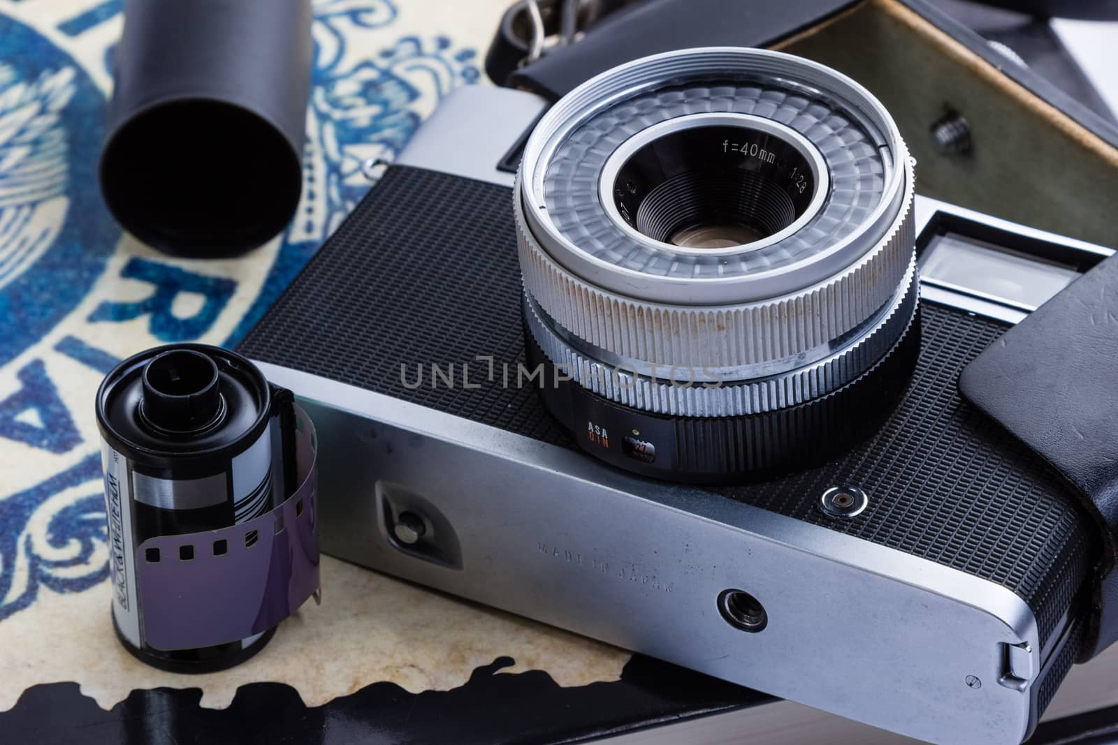 An old Rangefinder camera with film and canisters placed on a book.