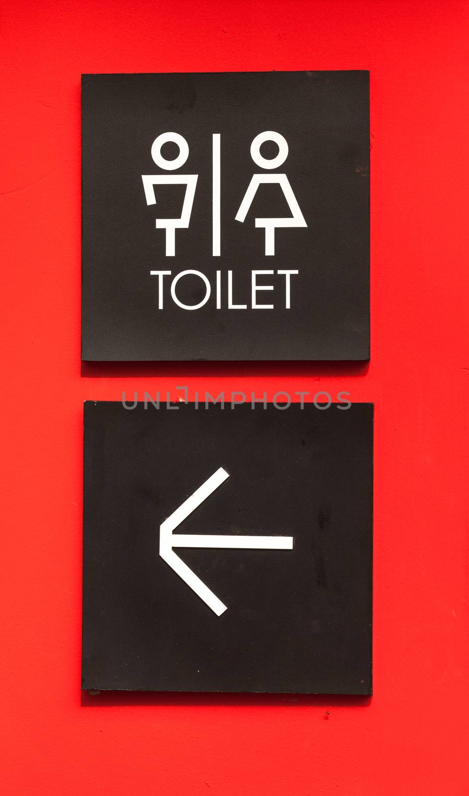 Unisex restroom or toilet and arrow sign on red wall style boutique .
