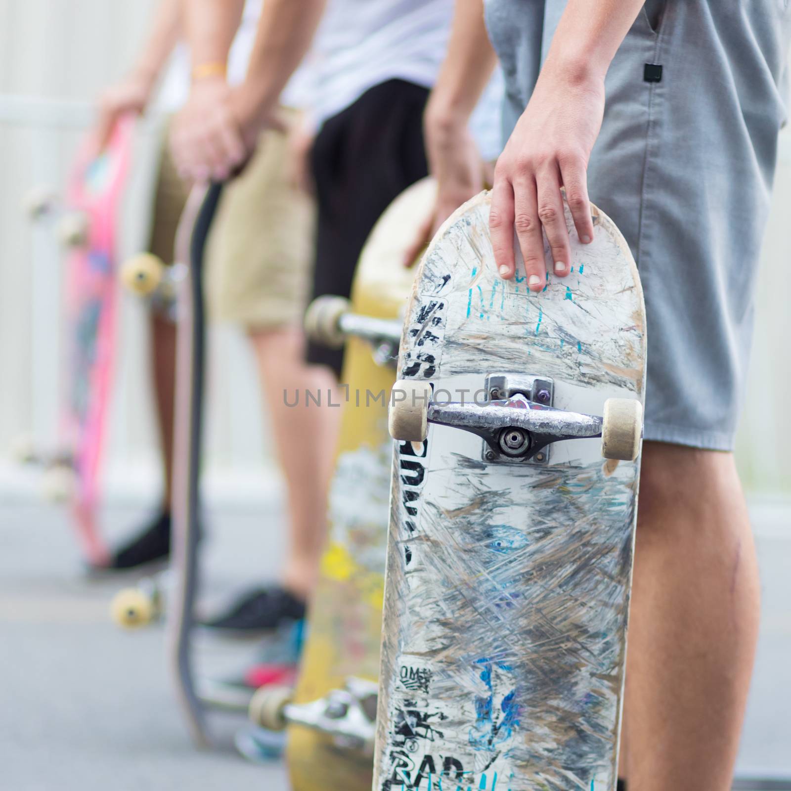 Young skateboarders skateboarding on the street. Group of friends standing in a row with skateboards in their hands. Urban life. Youth subculture.