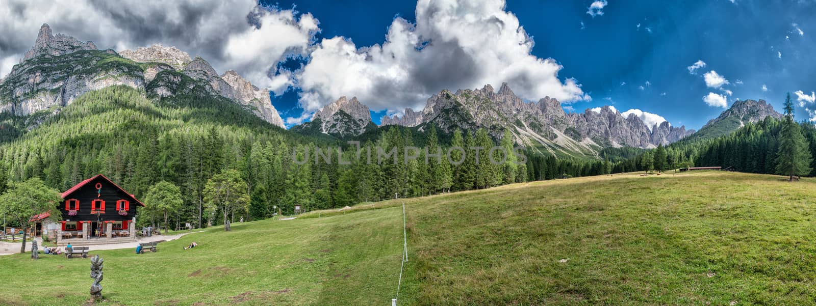 Beautiful panoramic view of mountains, hut and meadows.