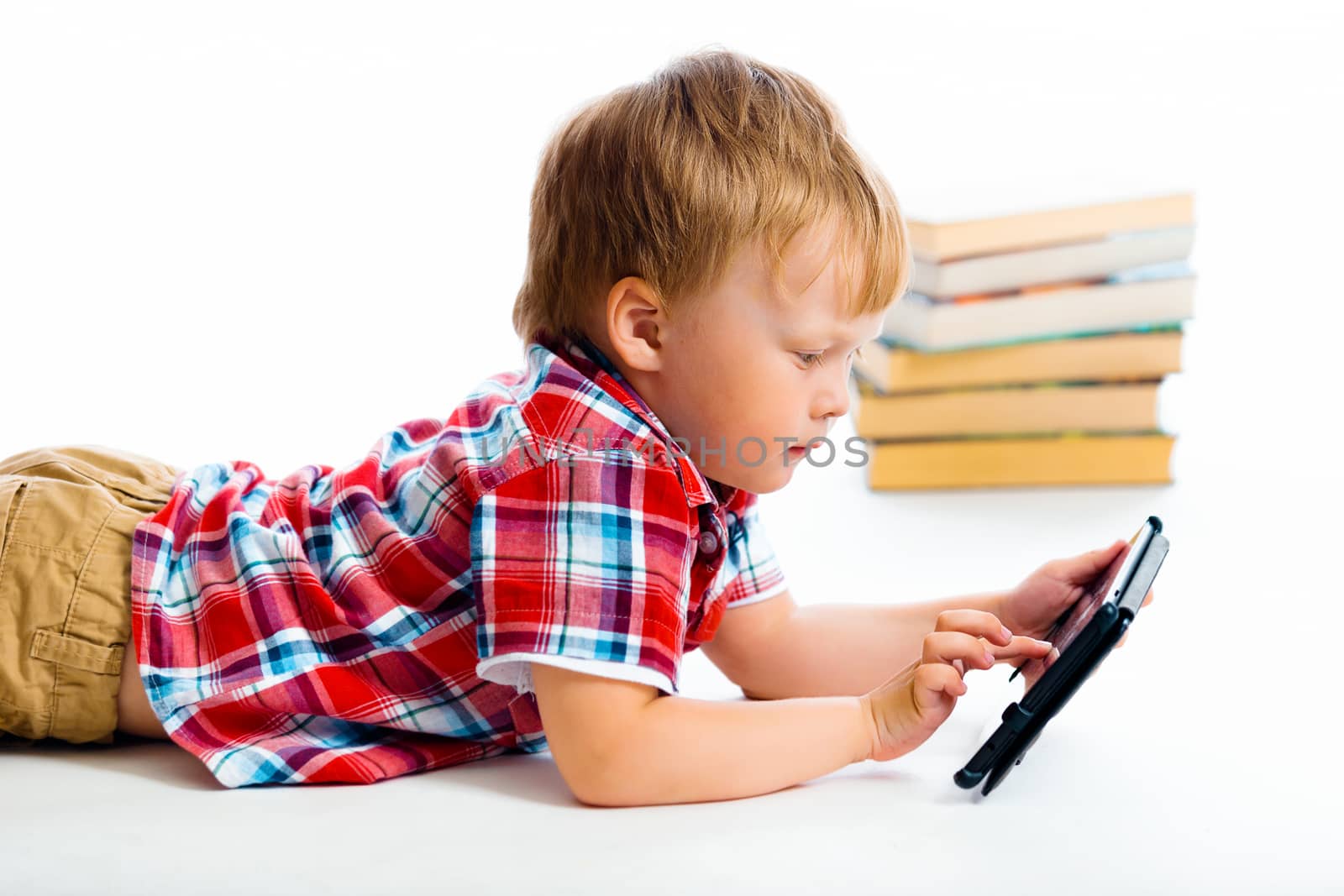 A small boy with tablet computer lying on the floor