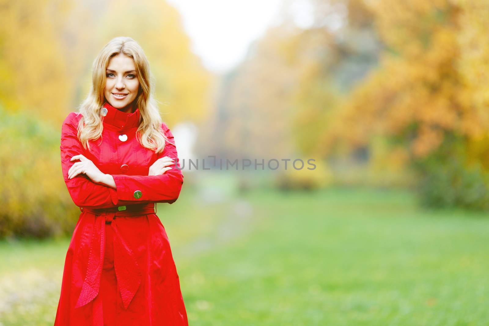 Young woman in red coat walking in autumn park