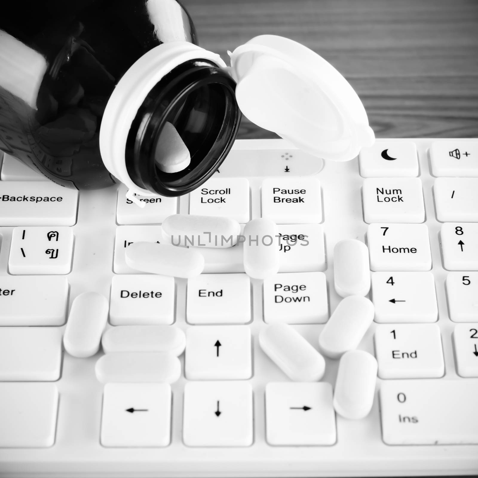 pills on keyboard computer on wooden background concept technology addiction black and white color tone style