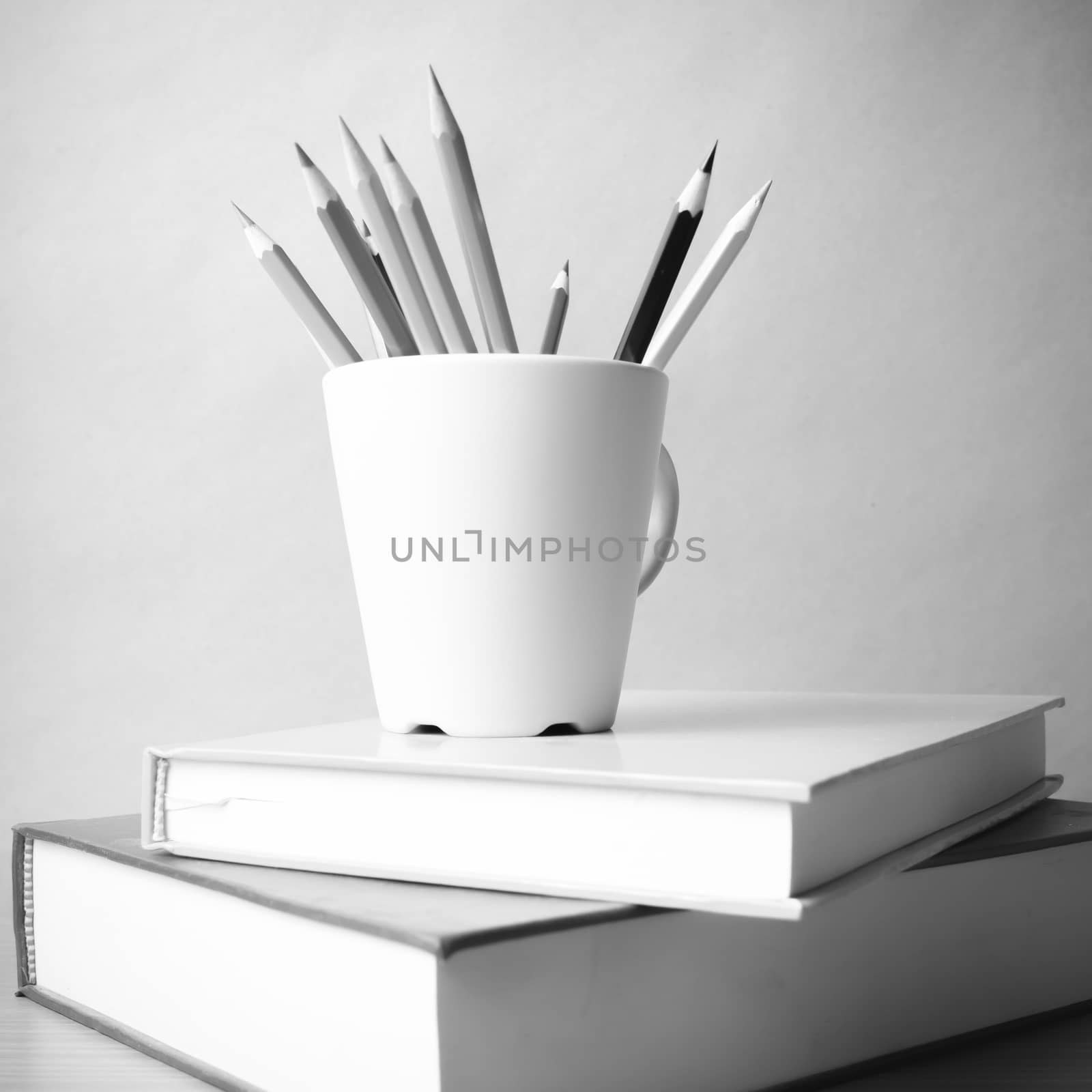 stack of book with color pencil on wood table background black and white color tone style