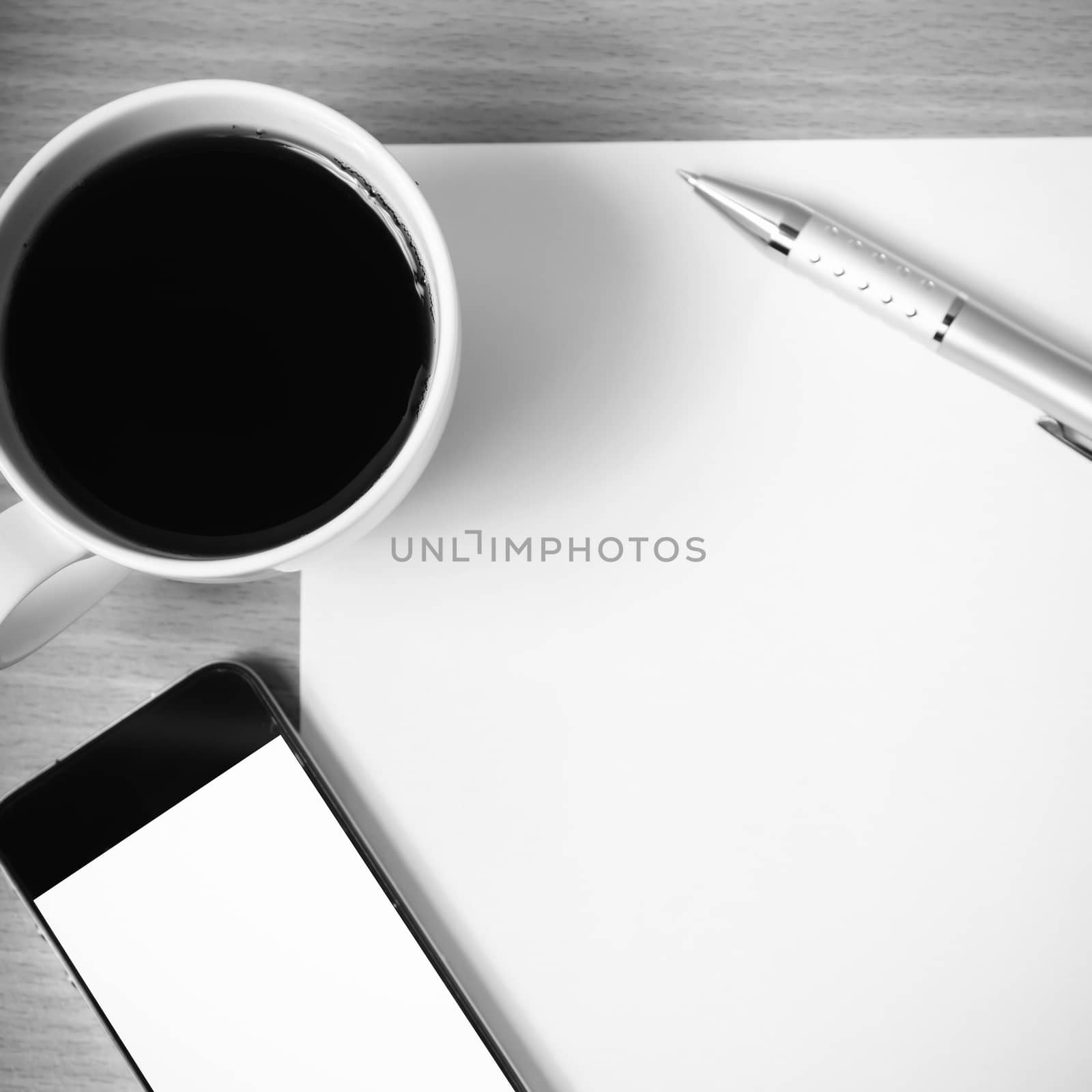 paper and pen with coffee cup and smart phone on wood background black and white color tone style