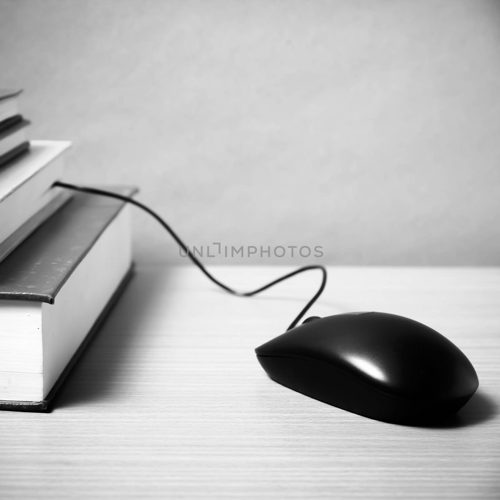 book and computer mouse on wood background black and white color tone style