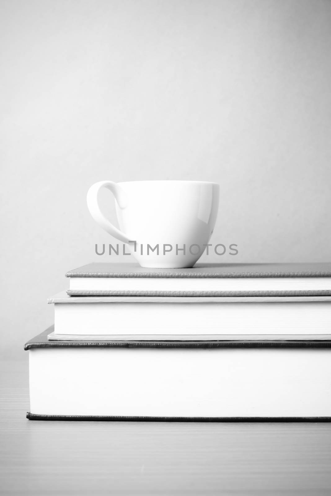 stack of book with coffee cup on wood table background black and white color tone style