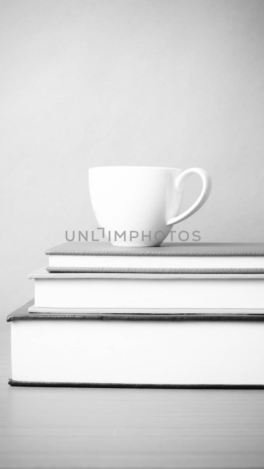 stack of book with coffee cup on wood table background black and white color tone style