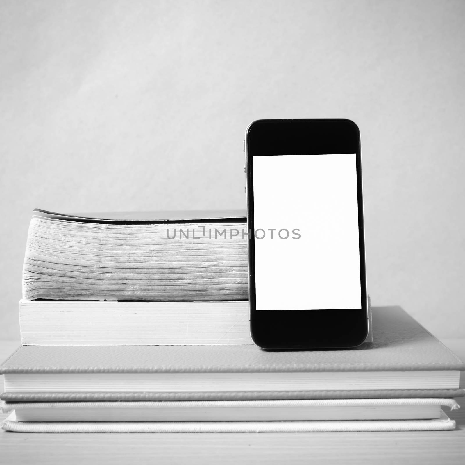 stack of book and smart phone on wood background black and white color tone style