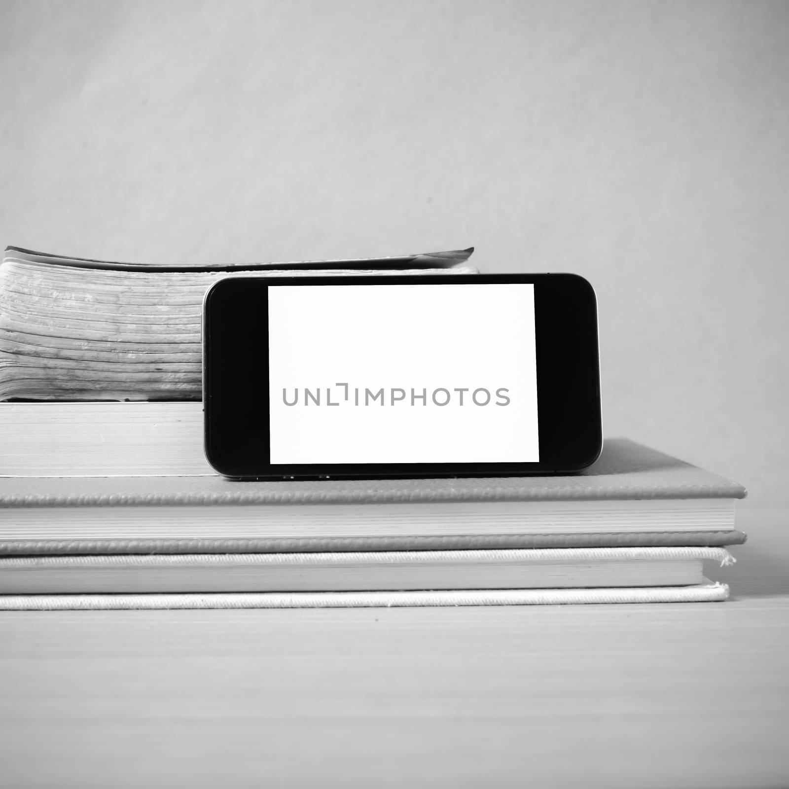 stack of book and smart phone on wood background black and white color tone style