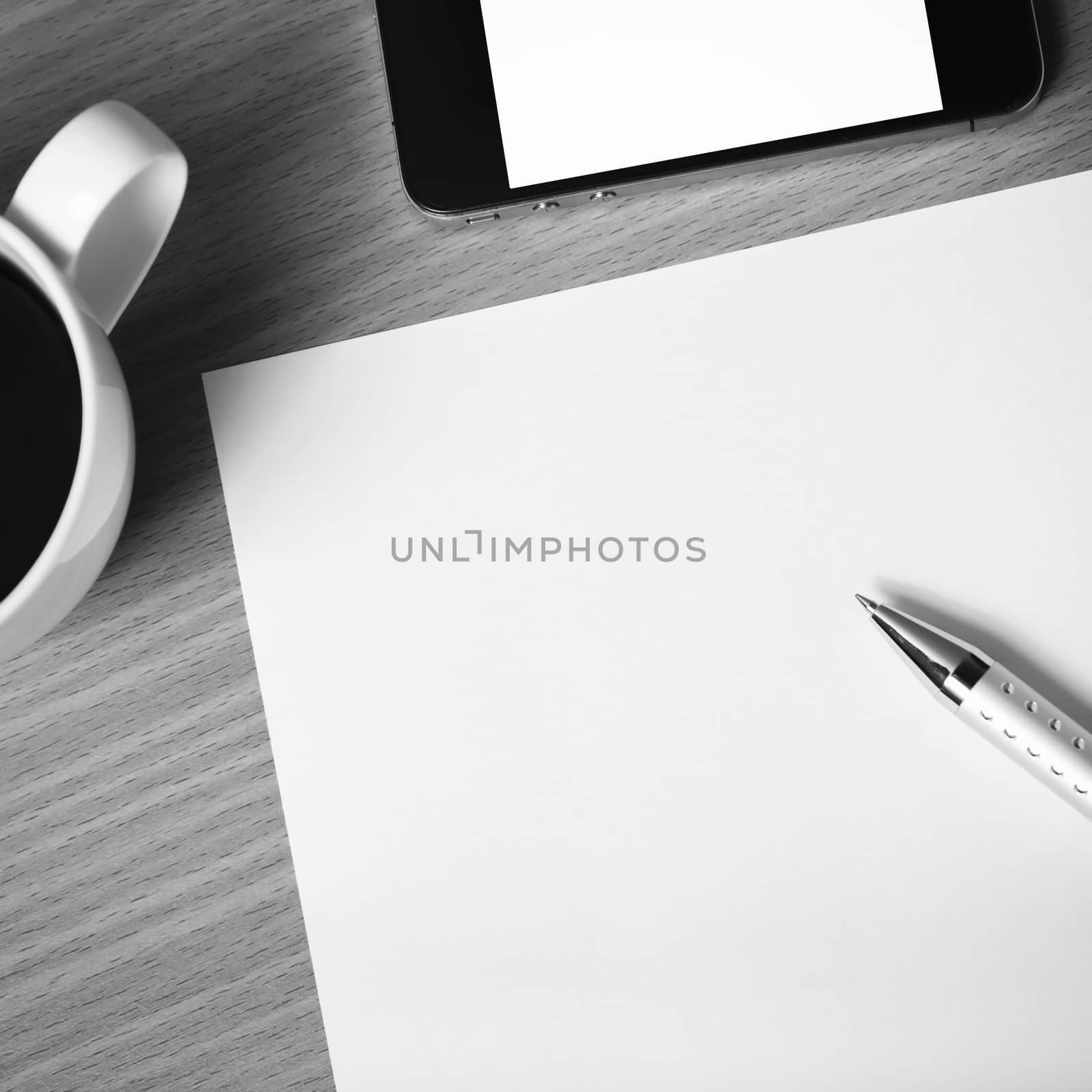 paper and pen with coffee cup and smart phone on wood background black and white color tone style