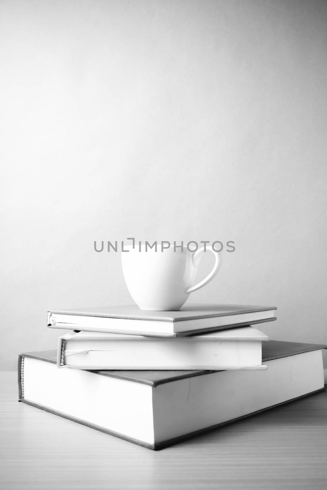 stack of book with coffee cup on wood table background black and white color tone style
