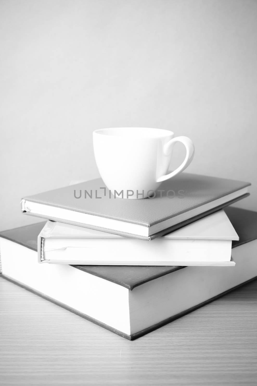 stack of book with coffee cup on wood table background black and white color tone style