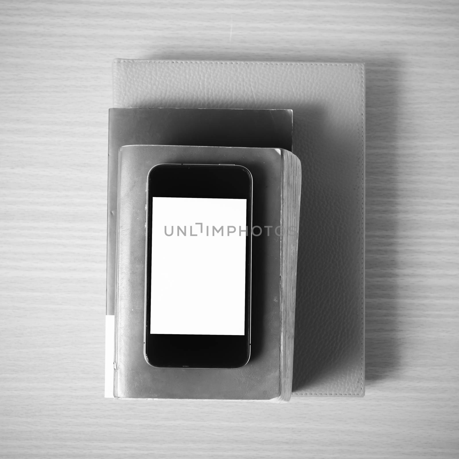 stack of book and smart phone on wood background black and white color tone style