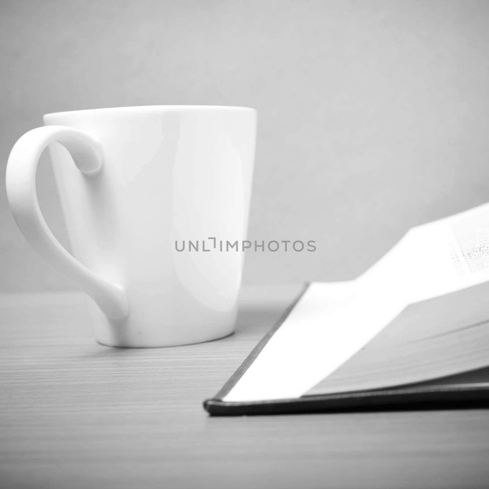 book and coffee mug on wood background black and white tone style