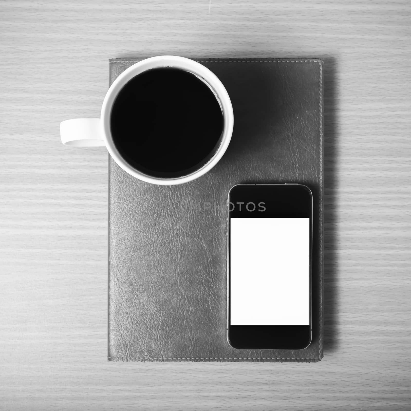 smart phone and coffee cup on book on wood background black and white color tone style