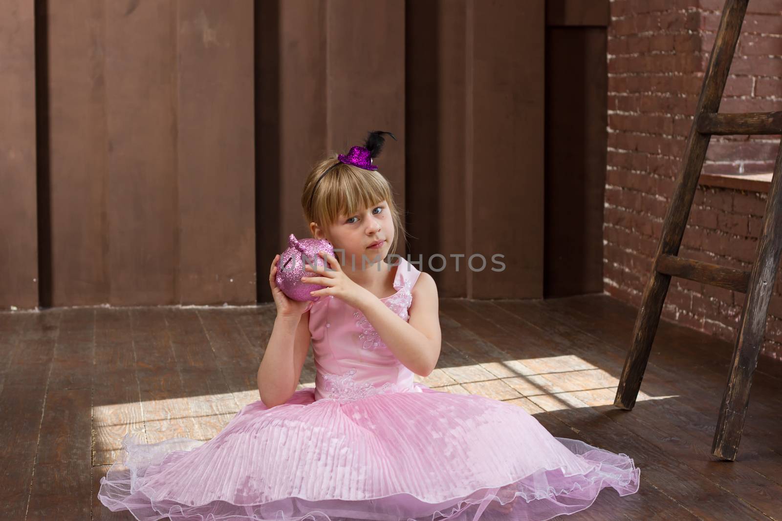 Girl 6 years old in a pink dress with a piggy bank in his hands. In Room