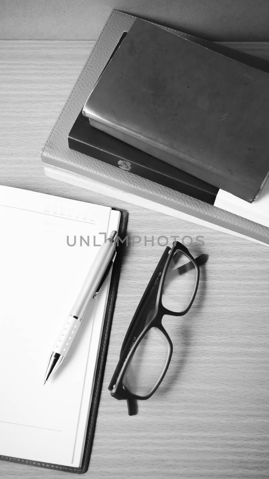 open notebook with stack of book on wood background black and white color tone style
