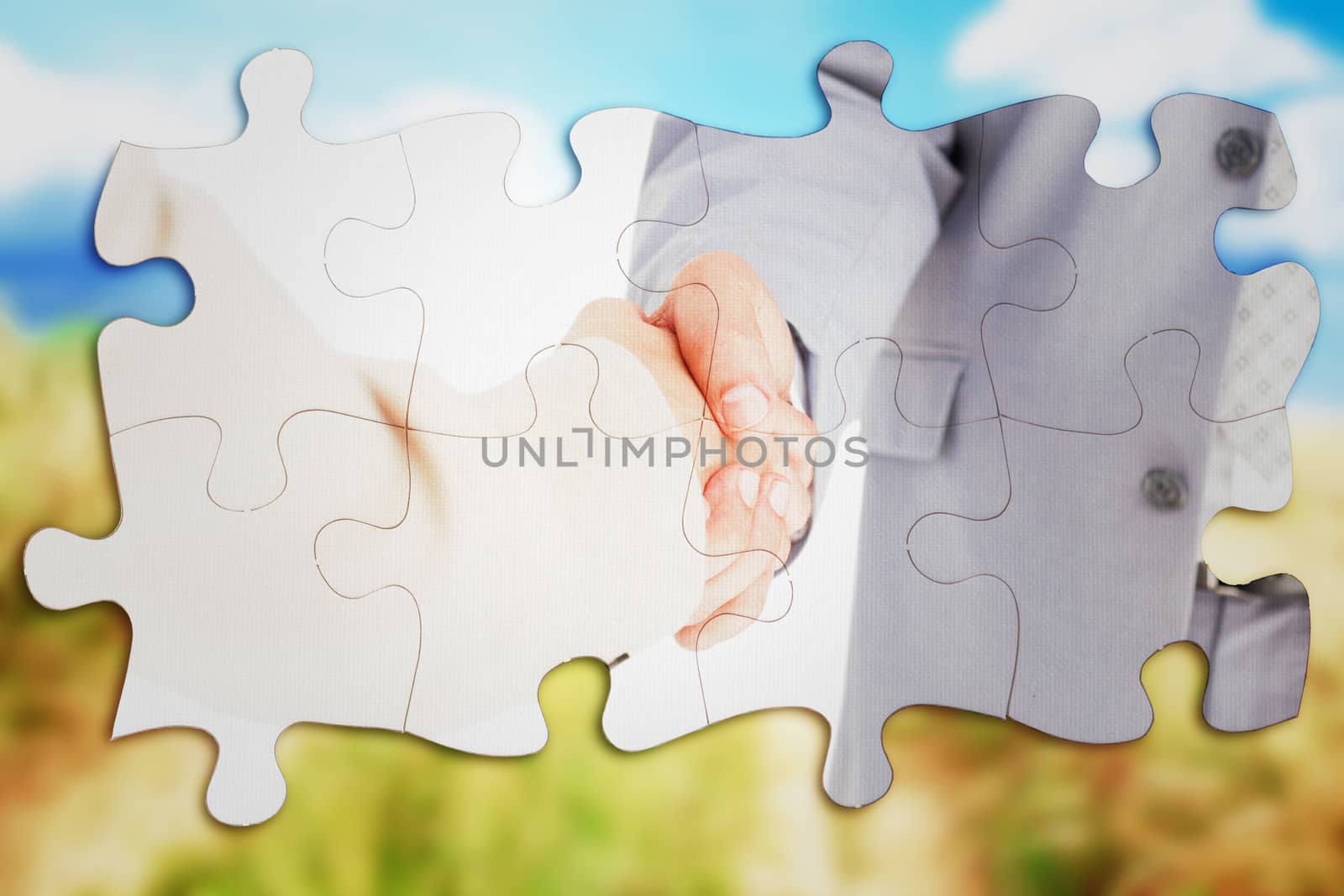 People in suit shaking hands against blue sky over sand dunes