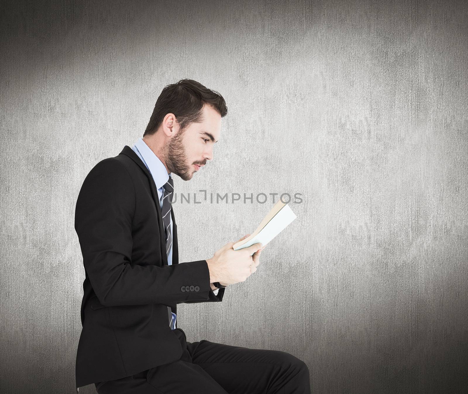 Composite image of businessman lying on the floor while reading a book by Wavebreakmedia